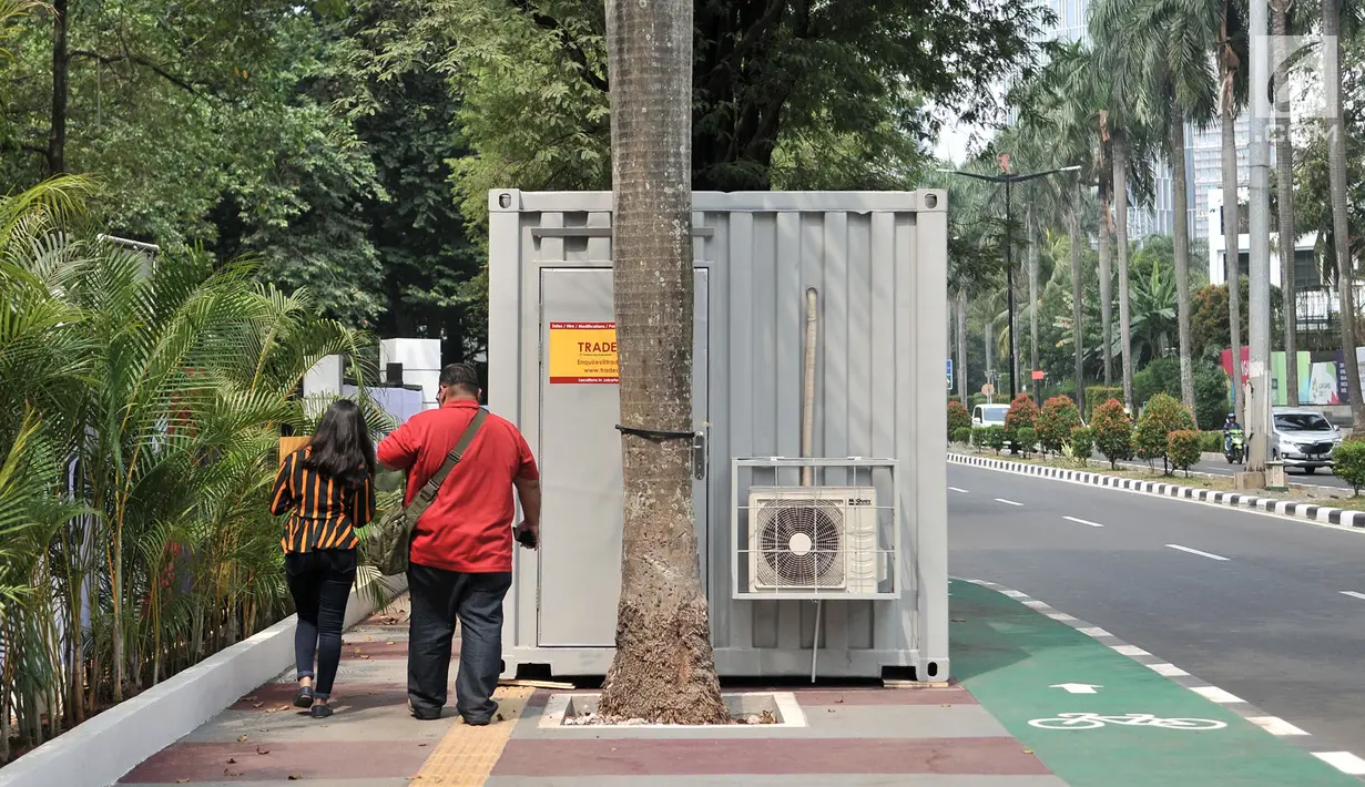 Pejalan kaki menghindari kontainer tiket Asian Games 2018 yang berdiri di sepanjang trotoar Jalan Pintu 1 Senayan, Jakarta, Selasa (7/8). (Merdeka.com/Iqbal Nugroho)
