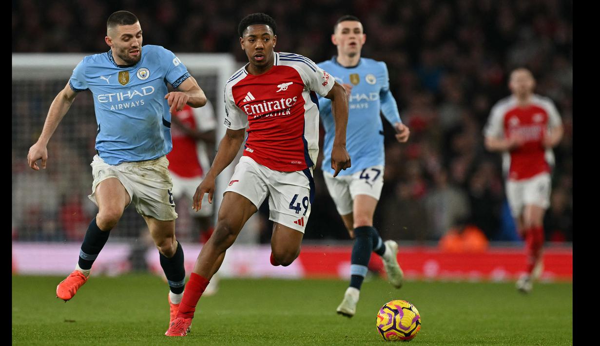 Pemain Arsenal, Myles Lewis-Skelly menggiring bola dibayangi sejumlah pemain Manchester City dalam laga lanjutan Liga Inggris 2024/2025 di Emirates Stadium, London, Minggu (03/02/2025). (AFP/Glyn Kirk)