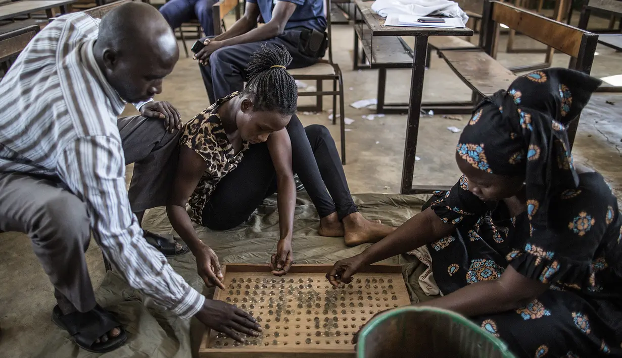 Sejumlah petugas menghitung kelereng yang akan digunakan untuk pemilihan Presiden Gambia di distrik Tallinding, Serekunda, Gambia (30/11). Mekanisme pemungutan suaranya hampir sama dengan negara demokrasi lainnya. (AFP/Marco Longari)