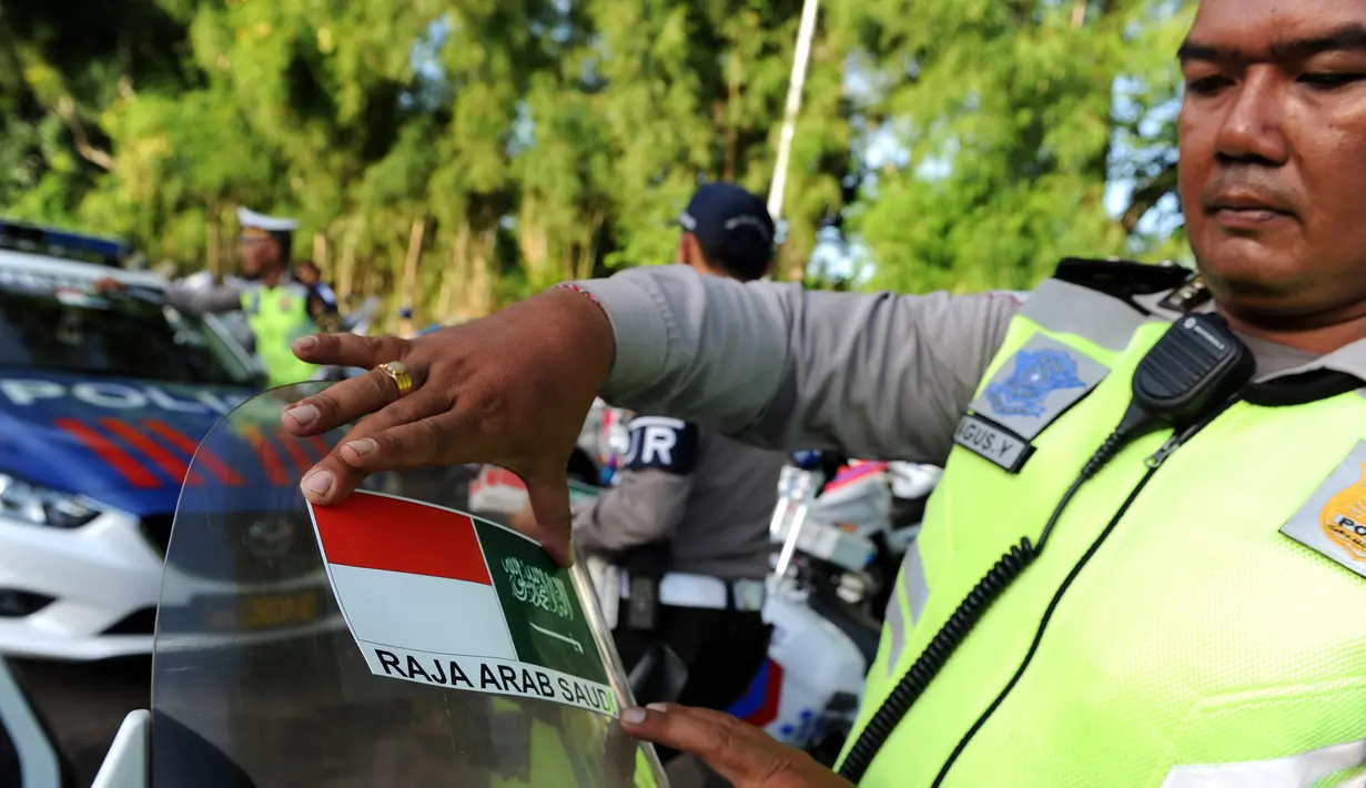 Polisi menempelkan stiker bendera Indonesia dan Arab Saudi selama persiapan menyambut Raja Arab Saudi Salman bin Abdulaziz,Nusa Dua, Bali (2/3). Raja Salman akan berlibur di Bali tanggal 4 sampai 9 Maret. (AFP Photo / Sonny Tumbelaka)