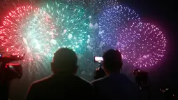 Penonton menyaksikan pertunjukan kembang api dari salah satu peserta dalam puncak kompetisi Pyromusical Internasional ke-9 di Filipina, Sabtu (24/3). Peserta kompetisi adalah para maestro kembang api kelas dunia dari berbagai negara. (AP/Bullit Marquez)