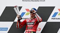 Pembalap Ducati Lenovo, Francesco Bagnaia memegang trofi kemenangan di atas podium MotoGP Indonesia 2023 di Sirkuit Mandalika, Lombok, NTB, Minggu (15/10/2023). Bagnaia kembali memuncaki klasemen MotoGP 2023. Ia sempat tergeser di posisi kedua setelah Jorge Martin memenangkan Sprint Race pada Sabtu (14/10/2023). (AFP/Sonny Tumbaleka)