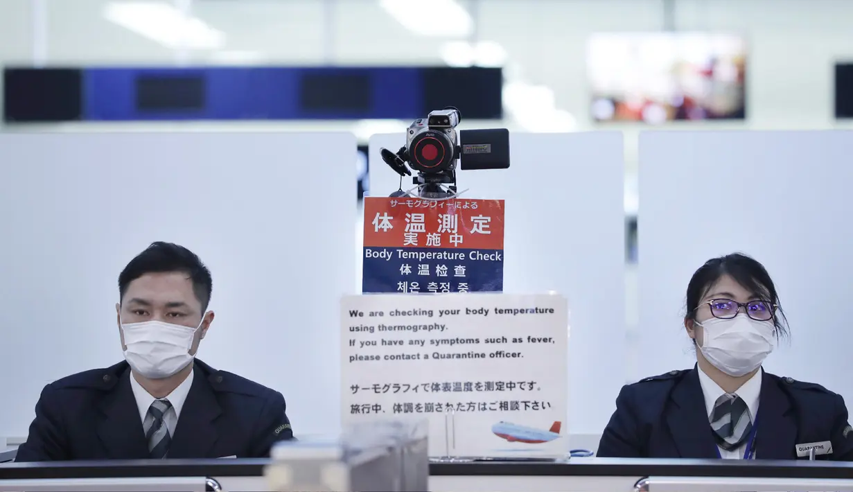 Petugas berjaga di stasiun pemeriksaan kesehatan ketika mereka mengamati penumpang yang tiba dalam penerbangan dari Wuhan, China, tempat virus corona ditemukan dan telah menyebar di bandara Narita, Jepang (16/1/2020). (AFP Photo/Jiji Pers/Str)