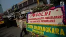 Warga melintasi karangan bunga di Halaman Polres Jakarta Barat, Jumat (23/11). Puluhan karangan bunga yang dikirimkan warga tersebut diberikan guna mendukung pihak kepolisian dalam memberantas aksi premanisme di Jakarta Barat. (Liputan6.com/Faizal Fanani)