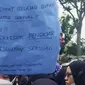 Salah seorang mahasiswi membawa kertas bertuliskan protes terhadap vonis bebas terdakwa pencabulan mahasiswi Universitas Riau. (Liputan6.com/M Syukur)