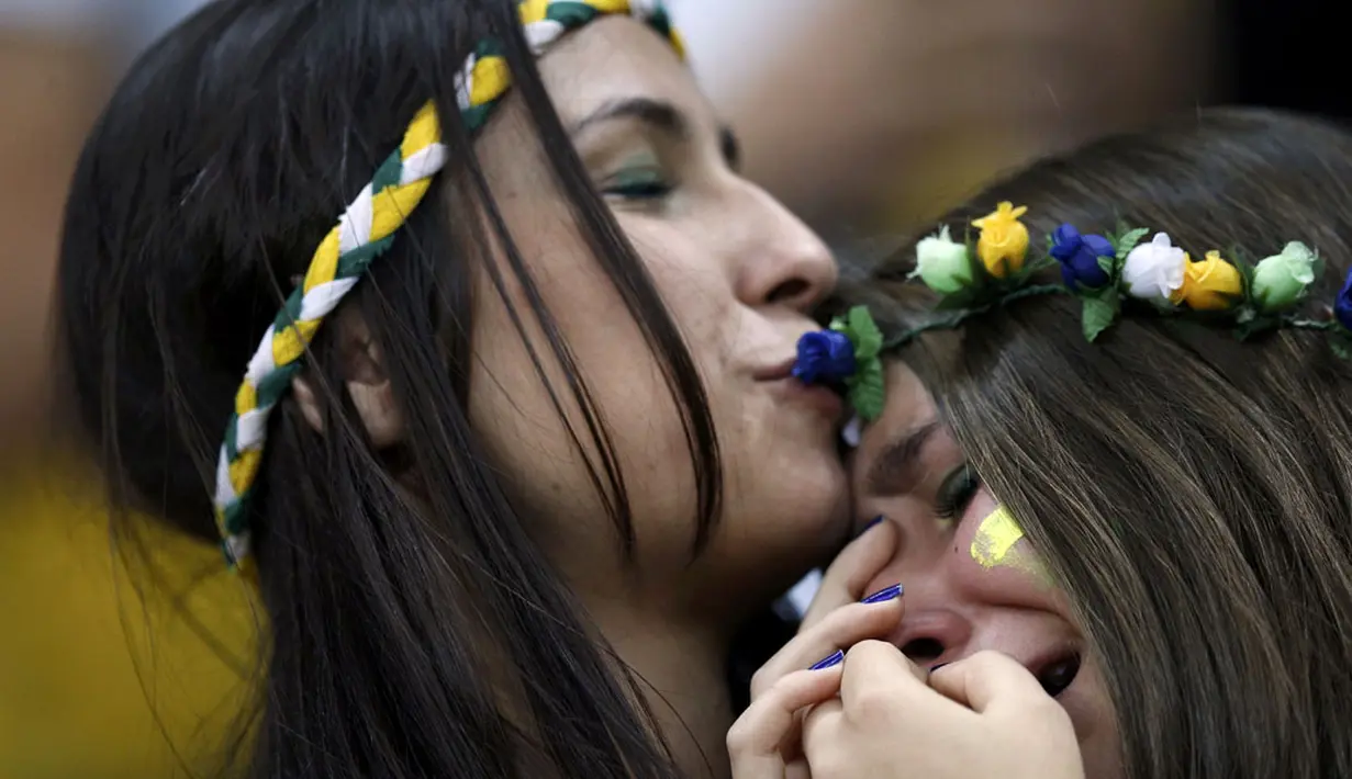 Suporter Timnas Brasil berpelukan menahan kesedihan menyaksikan kegagalan tim asuhan Luiz Felipe Scolari dikalahkan Belanda 0-3 di Stadion Nasional Brasilia, (13/7/2014). (REUTERS/Ueslei Marcelino)