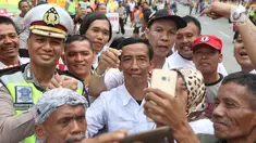 Seorang pria berwajah mirip Presiden Joko Widodo (Jokowi) berswafoto bersama warga yang memadati sekitar Gedung Graha Saba Buana, Solo, Rabu (8/11). Pria bernama David itu beberapa saat berhasil mengecoh warga. (Liputan6.com/Angga Yuniar)