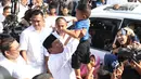 Calon Presiden no urut 02, Prabowo Subianto mengangkat seorang anak usai menggunakan hak pilihnya pada Pemilu 2019 di TPS 041 Kampung Curug, Desa Bojong Koneng, Babakan Madang, Kabupaten Bogor, Jawa Barat, Rabu (17/4). Prabowo didampingi Fadli Zon. (Liputan6.com/Helmi Fithriansyah)