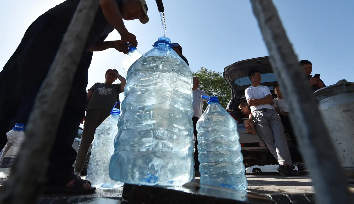 Warga Kyrgyz mengambil air dari mata air artesis di sebuah masjid dekat distrik Archa-Beshik di ibu kota Bishkek pada 8 Juni 2023. Penduduk ibu kota Kyrgyz berkumpul di sekitar lubang bor dengan botol plastik, satu-satunya cara bagi mereka untuk mendapatkan air setelahnya awal musim panas yang kering. (VYACHESLAV OSELEDKO / AFP)