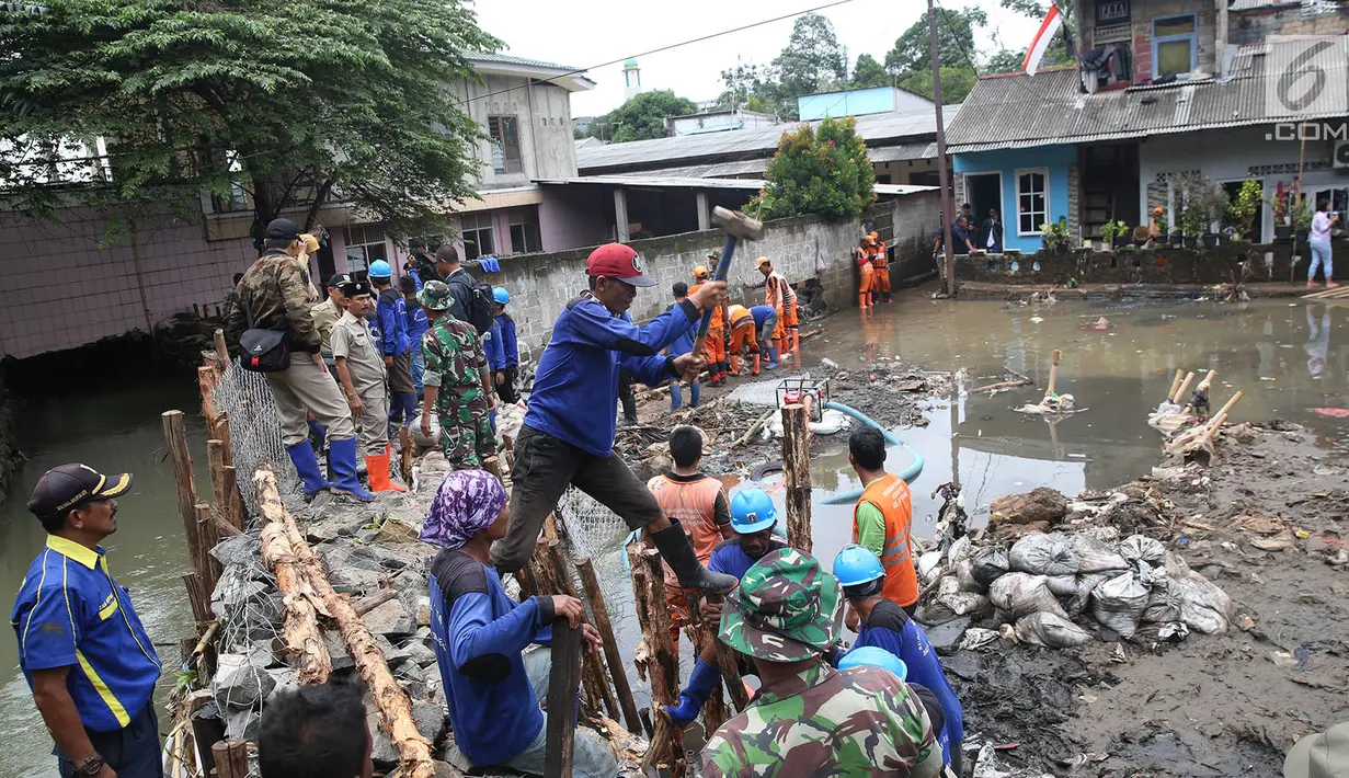 Petugas gabungan bergotong royong memperbaiki tanggul yang jebol di Kelurahan Jatipadang, Jakarta Selatan, Selasa (12/12). Terpantau anggota TNI, PPSU dan Suku Dinas Sumber Daya Air tengah memperbaiki tanggul. (Liputan6.com/Immanuel Antonius)