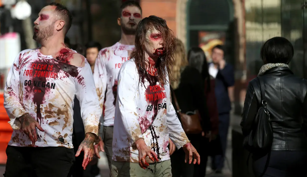 Aktivis PETA berdandan menyerupai zombie berbaur dengan pejalan kaki di depan sebuah restoran cepat saji di Sydney, Australia, Kamis (15/6). Aksi tersebut sebagai bentuk protes terhadap konsumsi daging dan mempromosikan vegetarian. (AP Photo/Rick Rycroft)