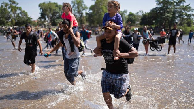 Migran Amerika Tengah membawa anak-anak saat berlari menyeberangi Sungai Suchiate dari Guatemala ke Meksiko, Ciudad Hidalgo, Meksiko, Senin (20/1/2020). Lebih dari seribu migran Amerika Tengah yang terdampar di Guatemala berjalan massal untuk menuju Amerika Serikat. (AP Photo/Santiago Billy)