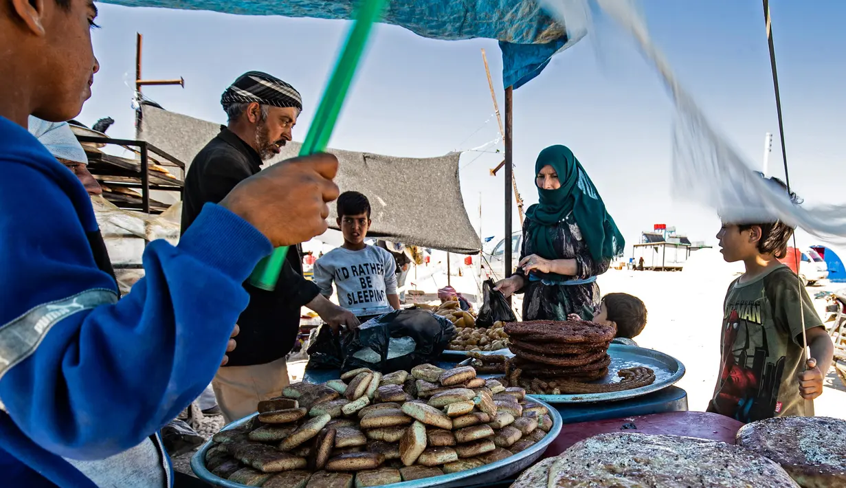 Warga Suriah yang terlantar menunggu pesanan permen mereka selama bulan suci Ramadan di kamp Washukanni untuk para pengungsi internal di provinsi Hasakeh di timur laut Suriah, (10/5/2020). (AFP/Delil Souleiman)