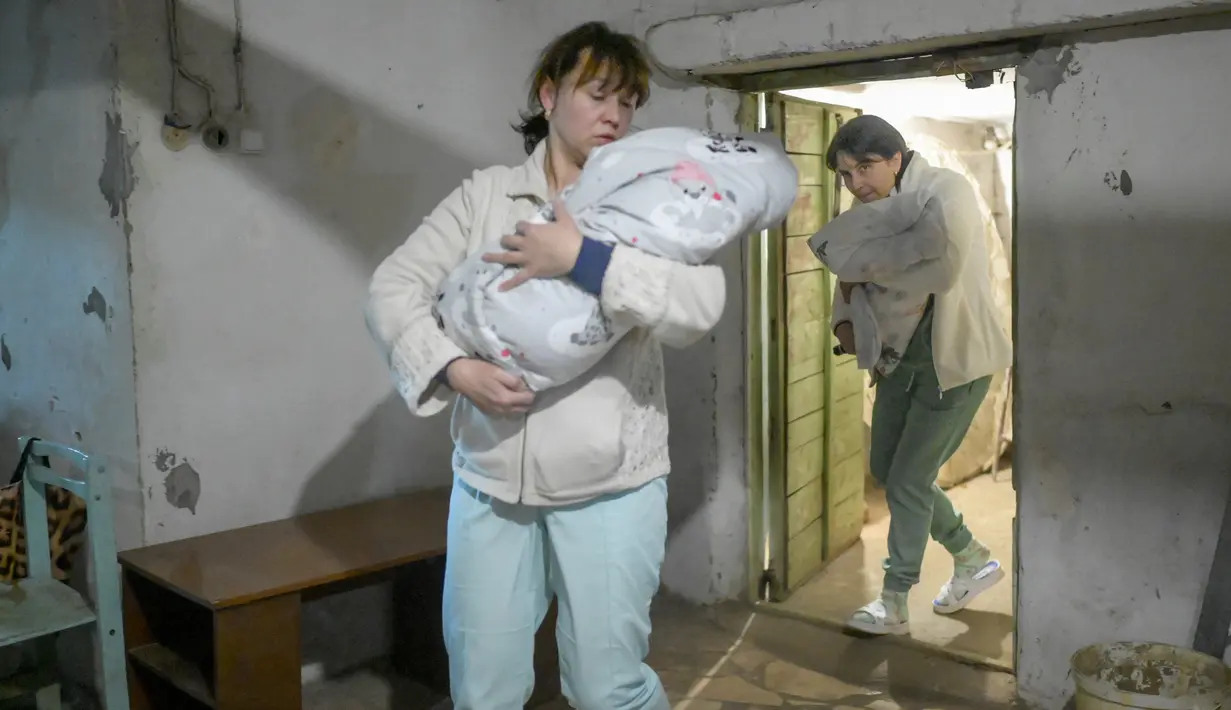 Perawat membawa bayi ke ruang bawah tanah rumah sakit bersalin saat peringatan sirene untuk serangan udara di Mykolaiv, Ukraina pada 14 Maret 2022. Mykolaiv, kota di tepi Laut Hitam dilaporkan menjadi target serangan pasukan Rusia selama berhari-hari. (BULENT KILIC/AFP)