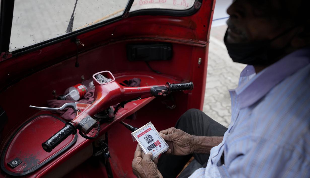 Seorang pengemudi bajaj menunggu untuk membeli bahan bakar dengan memegang kode QR di sebuah pompa bensin di Kolombo, Sri Lanka, Senin, 1 Agustus 2022.  Sri Lanka memperkenalkan distribusi bahan bakar menggunakan kode QR pada hari Senin sebagai bagian dari penerapan kuota mingguan untuk pengendara. (AP Photo/Eranga Jayawardena)