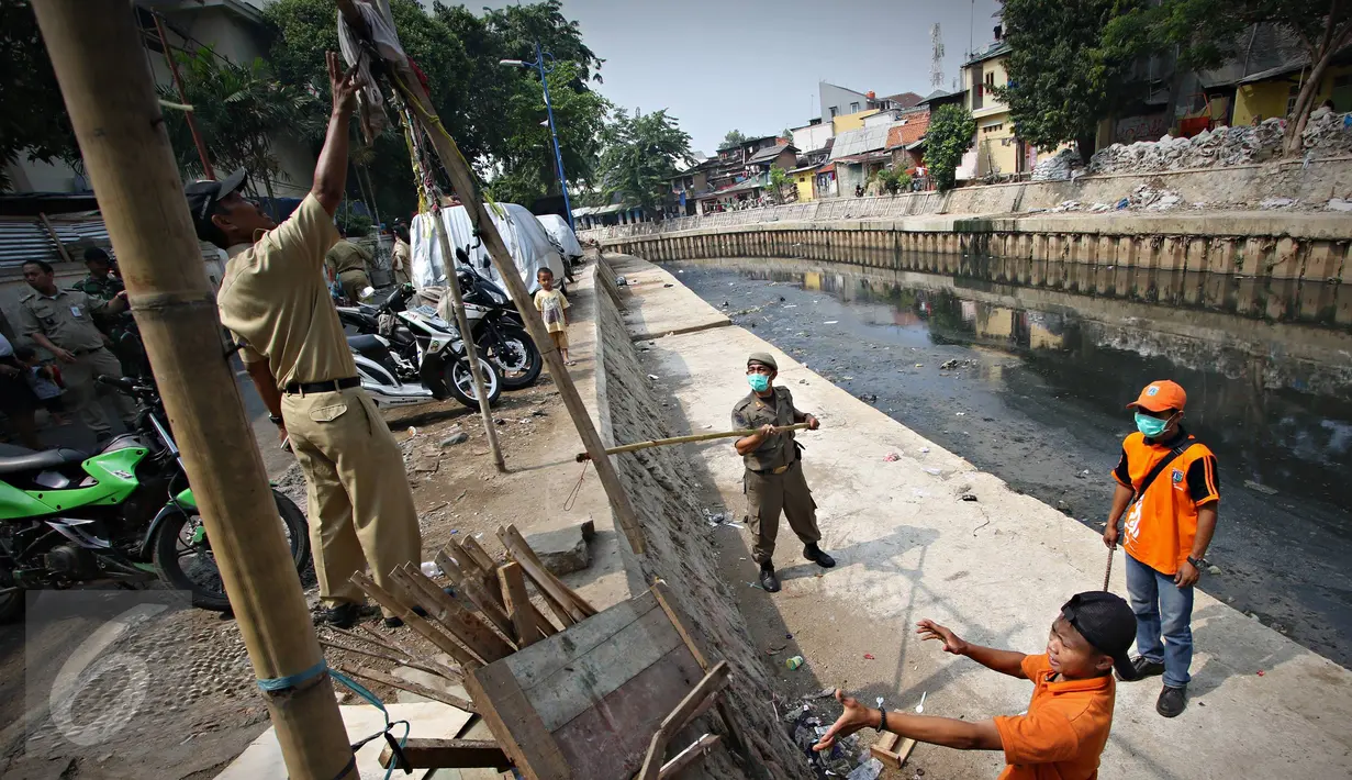 Petugas Sudin Kelautan Pertanian dan Ketahanan Pangan membongkar kandang saat penertiban unggas di bantaran Kali Ciliwung, Senen, Jakarta, Rabu (18/11). Penertiban dilakukan untuk mencegah penyebaran virus flu burung. (Liputan6.com/Immanuel Antonius)