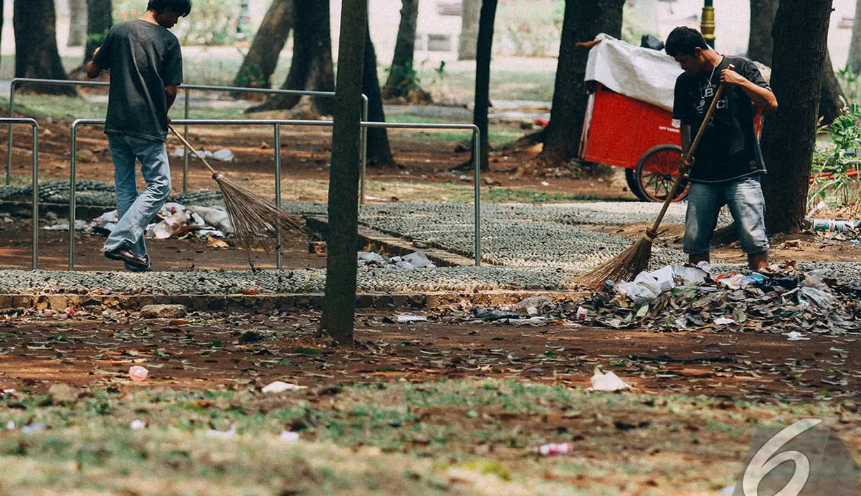 Para petugas sedang membersihkan sampah di kawasan Monas, Jakarta, Senin (27/10/2014). (Liputan6.com/Faizal Fanani)