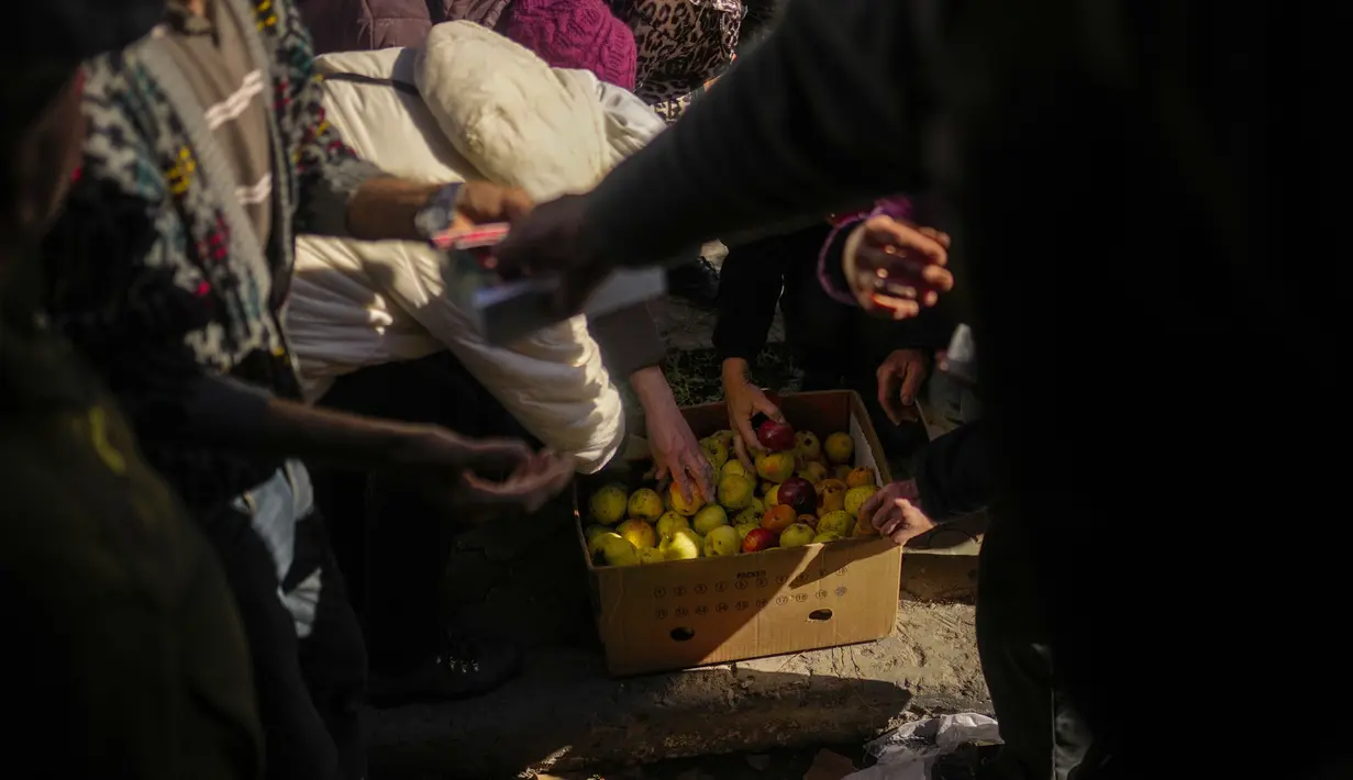Warga menerima makanan dan kebutuhan sehari-hari yang diberikan oleh relawan Ukraina di Izium, Ukraina, Rabu, 12 Oktober 2022. Jatuhnya Izium dengan cepat di provinsi Kharkiv merupakan kekalahan terburuk Rusia sejak pasukannya dipaksa mundur dari ibu kota Kyiv pada Maret. (AP Photo/Francisco Seco)