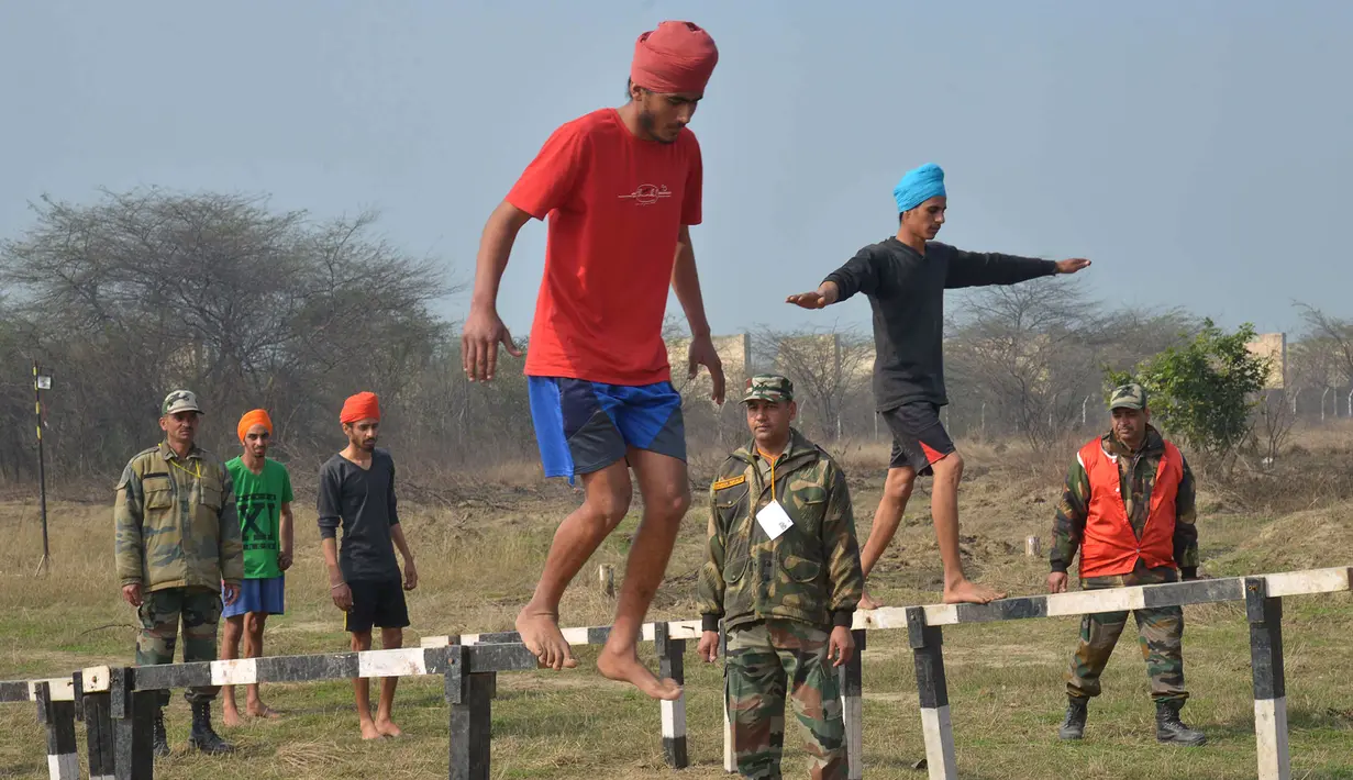 Para calon tentara India melakukan jalan di sebuah balok untuk mengatur keseimbangan tubuh dalam tes kebugaran fisik perekrutan tentara India di Khasa, Amritsar, (6/2). (AFP Photo / Narinder)
