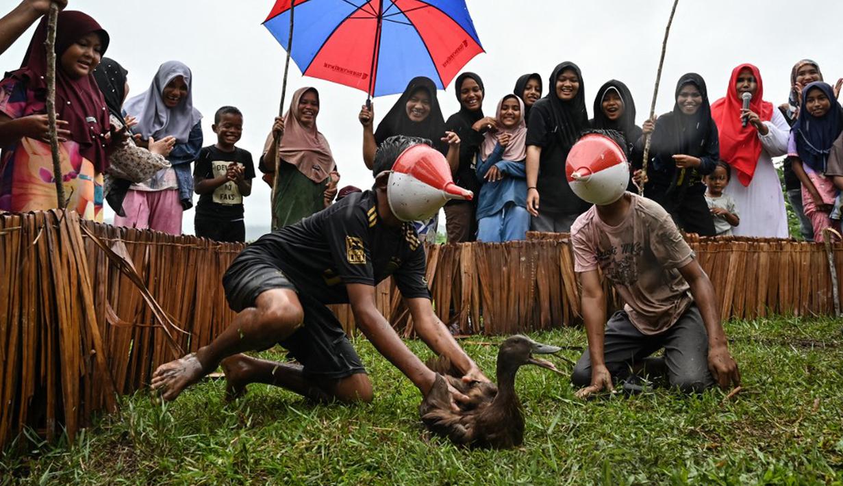 Anak-anak dengan wajah tertutup corong mengikuti lomba berburu bebek saat perayaan menjelang Hari Ulang Tahun (HUT) ke-78 Republik Indonesia (RI) di Desa Wisata Nusa, Banda Aceh, Aceh, Rabu (16/8/2023). (CHAIDEER MAHYUDDIN/AFP)