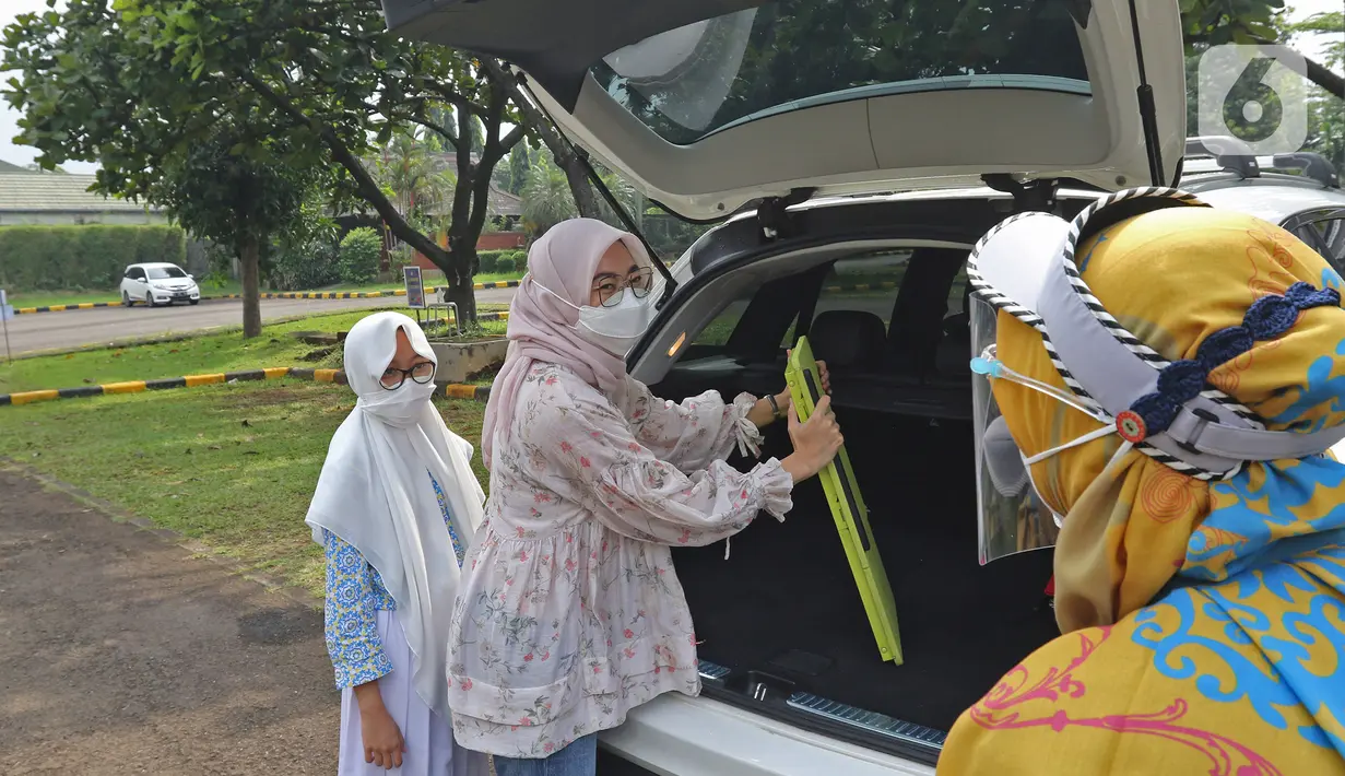 Orang tua murid mempersiapkan peralatan untuk mengikuti DRIL dengan konsep pembelajaran di ruang terbuka di Jakarta, Senin (5/4/2021). Pembelajaran tatap muka terbatas sebagai bentuk inovasi dan adaptasi dibidang pendidikan saat pandemi Covid-19 masih terjadi. (Liputan6.com/Herman Zakharia)