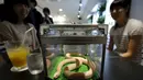 Pengunjung menikmati hidangan sambil ditemani ular  di sebuah kafe ular bernama 'Tokyo Snake Center' di distrik fashion Harajuku, Tokyo, 14 Agustus 2015. Sekali kunjungan, pengunjung hanya perlu membayar sekitar Rp108 ribu. (REUTERS/Toru Hanai)