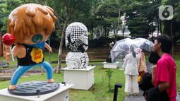 Pengunjung melihat karya seni yang ditampilkan dalam pameran Art Jakarta Gardens 2023 di Hutan Kota Plataran, Senayan, Jakarta Pusat, Selasa (7/2/2023). Pameran seni Art Jakarta Gardens kembali digelar tahun ini mulai dari tanggal 7 - 12 Februari 2023, dalam pameran ini, pengunjung dapat menjelajahi kombinasi presentasi karya seni rupa yang ditampilkan dari dalam dan luar ruangan dengan karya berupa patung, instalasi, dan objek dua dimensi. (Liputan6.com/Herman Zakharia)