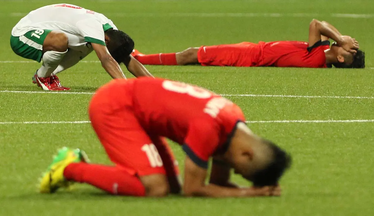 Ekspresi bersyukur Zulfiandi kontras dengan ekspresi kesedihan dua pemain Singapura U-23. (Bola.com/Arief Bagus)