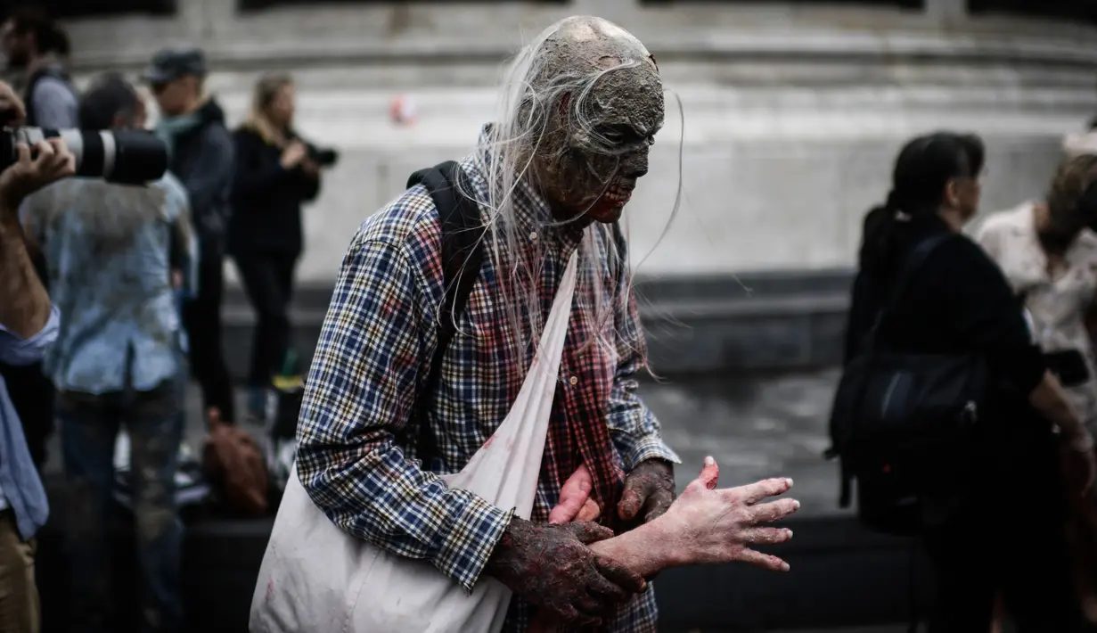 Penggemar film horor memakai kostum dan berdandan menyerupai zombie saat berpartisipasi dalam acara Zombie Walk di Place de la Republique, Paris, Sabtu (12/10/2019). Sejak 2008, acara Zombie Walk digelar untuk orang-orang yang terobsesi dengan mayat hidup. (Martin BUREAU / AFP)