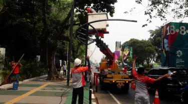 Petugas Suku Dinas PE Jakarta Pusat bersama Satgas PJU, mencabut dan menggeser tiang listrik dan lampu penerangan jalan yang menghalangi jalur sepeda di trotoar Jalan Asia Afrika dan Jalan Gelora, Senayan, Jakarta, Rabu (1/8). (Liputan6.com/Johan Tallo)