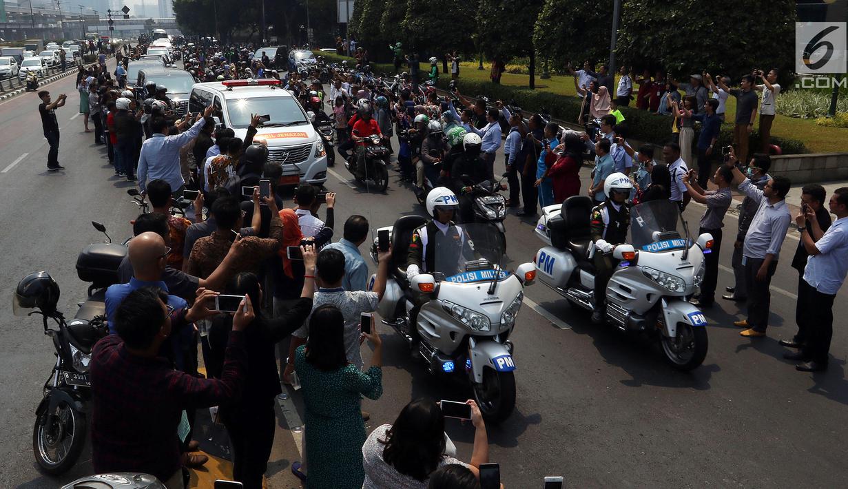 Warga antusias melihat iring-iringan mobil jenazah yang membawa almarhum Presiden ke-3 RI, BJ Habibie saat melintasi Jalan Gatot Subroto menuju TMP Kalibata, Jakarta, Kamis (12/9/2019). BJ Habibie meninggal pada Rabu (11/9/2019) setelah menjalani perawatan di RSPAD. (Liputan6.com/Johan Tallo)