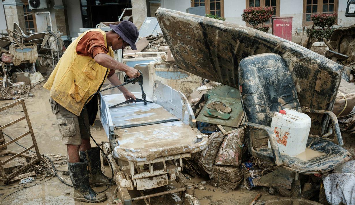 Sejumlah alat kesehatan disiram air bersih untuk pembersihan lanjutan. Tampak dalam foto, seorang petugas membersihkan peralatan medis yang terendam banjir bandang sekitar tiga bulan lalu di Rumah Sakit Daerah Aceh Tamiang, pada Selasa 16 Desember 2025. (Yasuyoshi CHIBA/AFP)