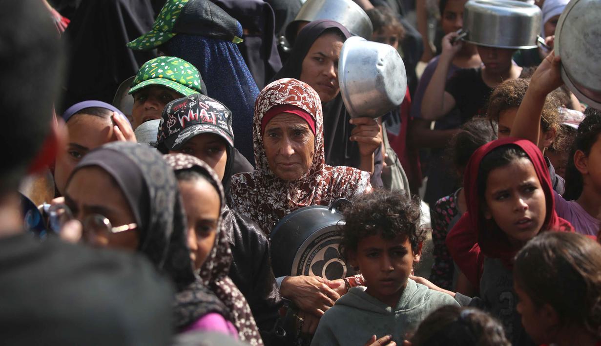 Warga Palestina yang terlihat sedang menunggu makanan di tempat penampungan yang telah dihuni banyak keluarga, di Nuseirat, pusat Jalur Gaza, pada 2 November 2025. Sejak gencatan senjata mulai diberlakukan, PBB bersama mitra-mitra kemanusiaannya telah mengumpulkan lebih dari 24.000 metrik ton bantuan dari perlintasan Jalur Gaza. (EYAD BABA/AFP)