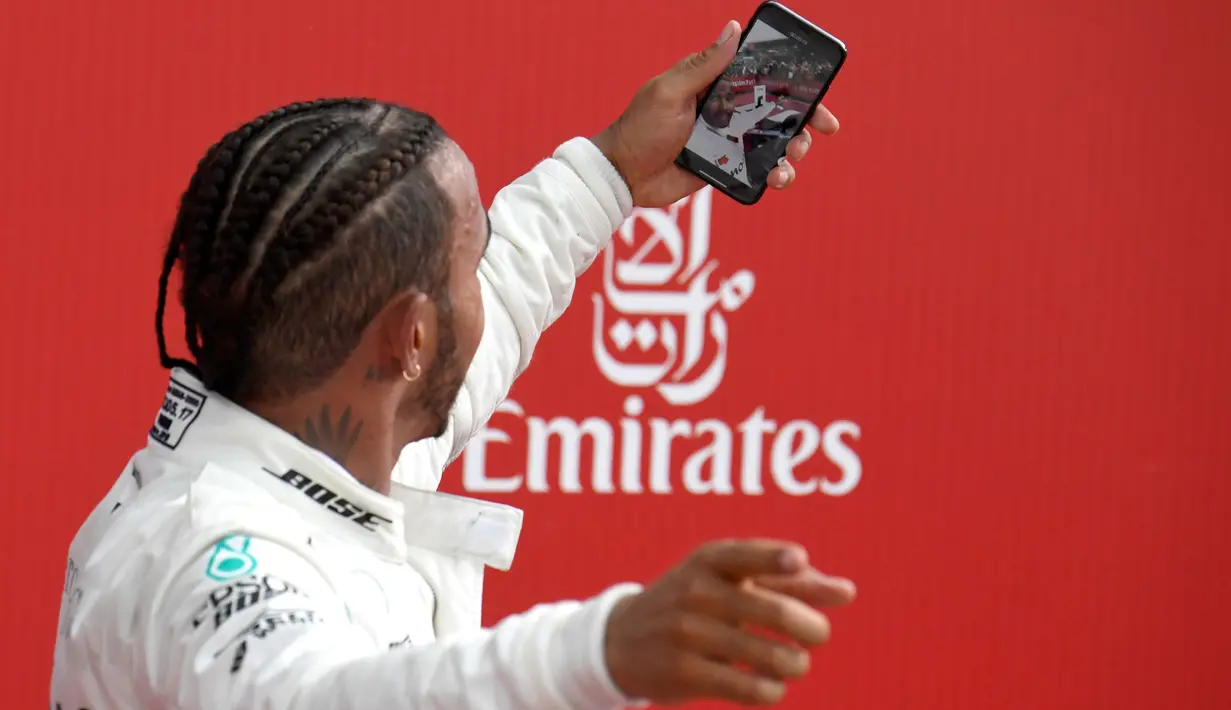 Pembalap Mercedes, Lewis Hamilton berswafoto setelah berhasil finish pertama pada balapan F1 GP Jerman di Sirkuit Hockenheim, Minggu (22/7). Hamilton menjuarai balapan F1 GP Jerman dengan catatan waktu 1 jam 32 menit 29,845 detik. (AP/Jens Meyer)