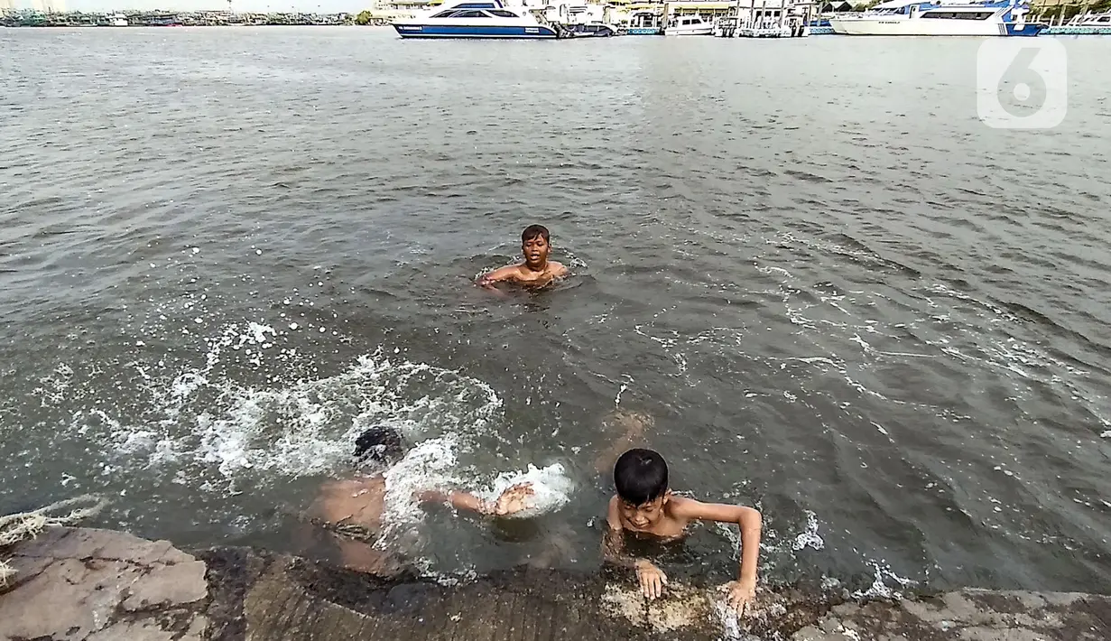 Anak-anak berenang di dermaga saat banjir rob merendam Pelabuhan Kali Adem, Muara Angke, Jakarta, Kamis (22/10/2020). Banjir rob yang merendam kawasan Pelabuhan Kali Adem sejak lima hari lalu dimanfaatkan oleh anak-anak setempat untuk berenang di sekitar dermaga. (merdeka.com/Iqbal S. Nugroho)