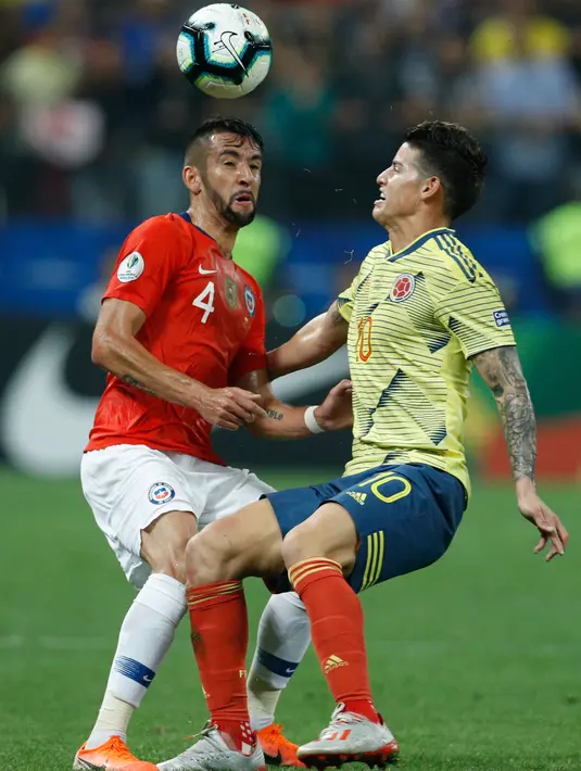 Bek Cile, Mauricio Isla berebut bola dengan pemain Kolombia, James Rodriguez pada perempat final Copa America 2019 di Arena Corinthians, Jumat (29/6/2019). Cile melaju ke semifinal Copa America 2019 setelah menundukkan Kolombia, 5-4, lewat adu penalti. (AP/Victor R. Caivano)