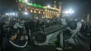 Dua mobil milik sebuah stasiun TV dirusak oleh massa di tengah unjuk rasa memprotes kenaikan harga BBM di Monterrey, Meksiko, Kamis (5/1). Kenaikan harga BBM mencapai 20 persen memicu kemarahan warga setempat. (Julio Cesar Aguilar/AFP)