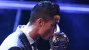 Bintang Real Madrid, Cristiano Ronaldo, mencium trofi pemain terbaik FIFA 2017 di London, Senin (23/10/2017) Ronaldo berhasil mengalahkan Lionel Messi dan Neymar yang juga menjadi nominasi. (AFP/Ben Stansall)