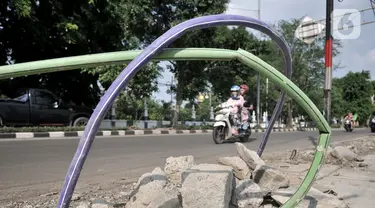 Kendaraan melintasi kabel proyek PLN yang terbengkalai di Jalan Jatinegara Kaum, Jakarta, Minggu (12/1/2020). Kurangnya pengawasan dalam penyelesaian proyek instalasi listrik bawah tanah PLN tersebut menyebabkan banyak kabel masih muncul di trotoar dan bahu jalan. (merdeka.com/Iqbal S. Nugroho)