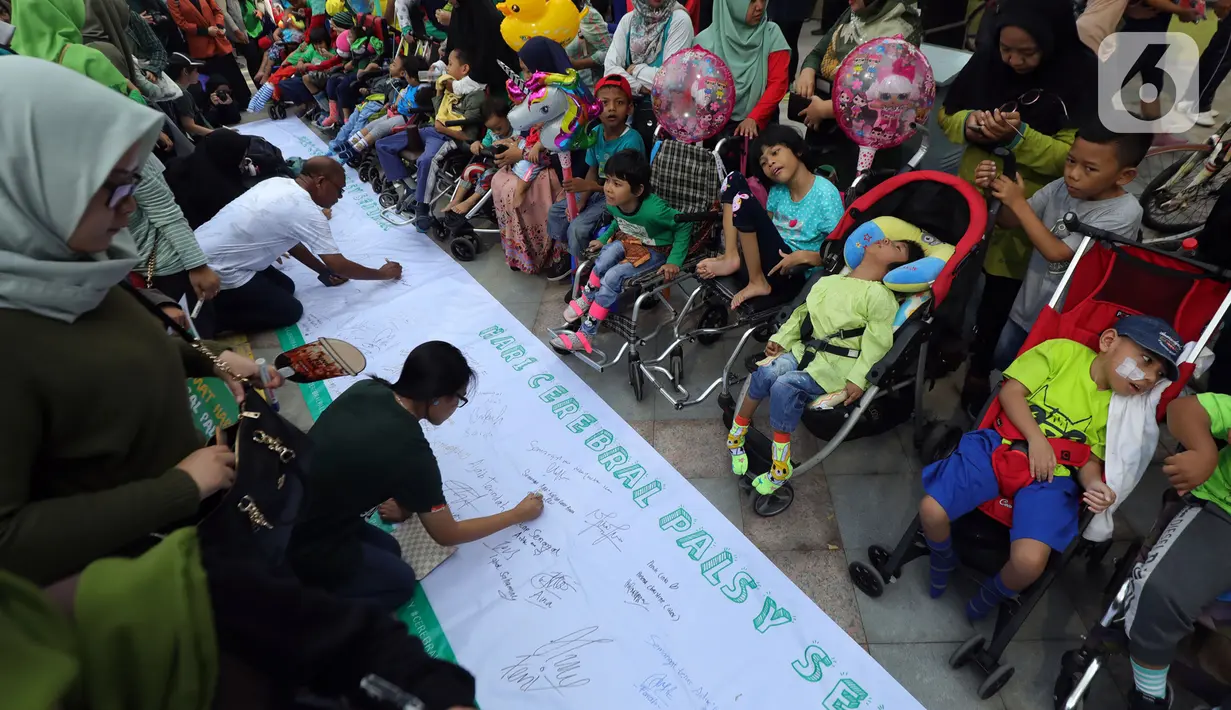 Masyarakat dan relawan menandatangani spanduk saat memperingati Hari Cerebral Palsy Sedunia di area Car Free Day, Jakarta, Minggu (13/10/2019). Peringatan yang jatuh 6 Oktober itu dimanfaatkan untuk mensosialisasikan dan menggalang kepedulian bagi penyandang cerebral palsy (Liputan6.com/Johan Tallo)