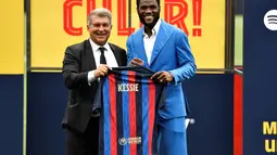 Gelandang baru Barcelona, Franck Kessie berfoto dengan Presiden Barcelona, Joan Laporta sambal memegang jersey barunya selama upacara presentasi di tempat latihan Joan Gamper di Sant Joan Despi, dekat Barcelona (6/7/2022). Pemain asal Pantai Gading ini merapat ke Camp Nou dengan status free transfer. (AFP/Pau Barrrena)