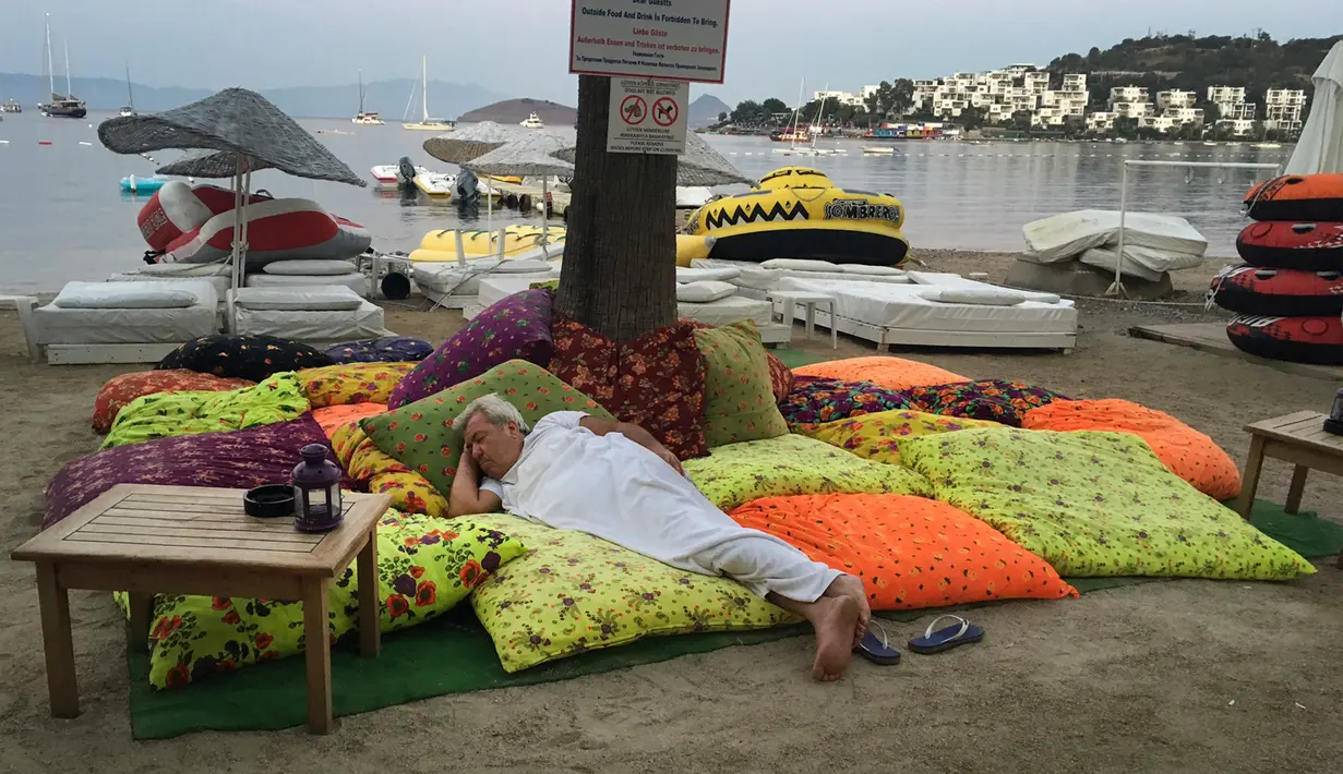 Seorang tamu hotel tidur di luar bangunan tempatnya menginap setelah gempa 6,7 SR melanda kota wisata Bitez di sebelah barat Turki, Jumat (21/7) dini hari. Gempa melanda Pantai Aegea di Turki dan sebagian pulau di Yunani. (AP/Ayse Wieting)