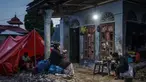Keluarga korban banjir bandang berbuka puasa Ramadan di tempat penampungan sementara berlatar rumah yang hancur di Ganting, Sumatera Barat pada 14 Maret 2024. (REZAN SOLEH/AFP)