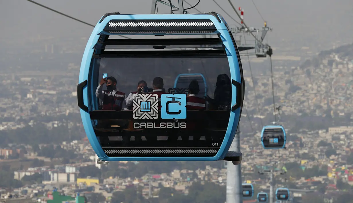 Pejabat dan jurnalis naik kereta gantung antara Stasiun Campos Revolucion dan Tlalpexco selama peresmian sistem angkutan umum udara baru yang disebut Cablebus di lingkungan Cuautepec, utara Mexico City, Meksiko, Kamis (4/3/2021). (AP Photo/Rebecca Blackwell)
