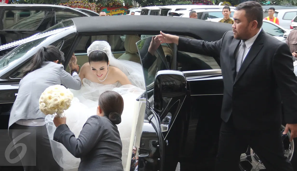 Aktris Sandra Dewi keluar dari mobil dan langsung menuju ke dalam gereja Katedral, Jakarta Pusat, Selasa (8/11). Sandra Dewi terlihat cantik dengan balutan gaun pengantin berwarna putih lengkap dengan crown di kepalanya. (Liputan6.com/Herman Zakharia)