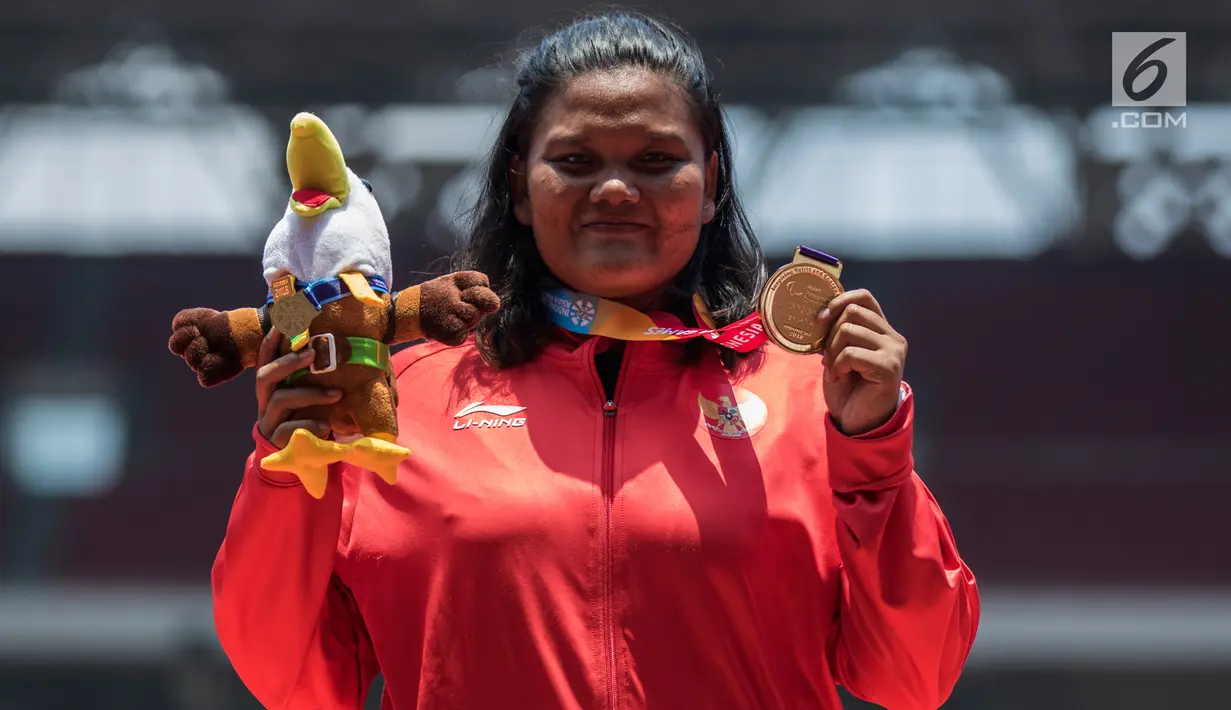 Atlet tolak peluru Indonesia, Suparniyati menunjukkan medali emas Asian Para Games 2018 di SUGBK, Jakarta, Senin (8/10). Suparniyati mencatat tolakan sejauh 10,75 meter. (Bola.com/Vitalis Yogi Trisna)