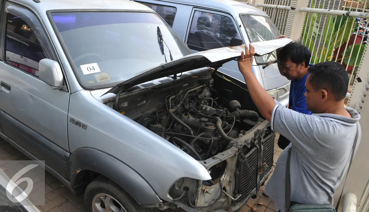 Calon peserta melihat kondisi mobil dinas yang akan dilelang di halaman KPK, Selasa (1/9/2015). KPK akan melelang 21 mobil dan 8 motor operasional yang sudah tidak digunakan lagi pada Rabu (2/9) melalui KPKNL Jakarta III. (Liputan6.com/Herman Zakharia)
