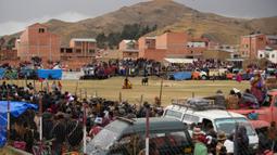 Penonton menyaksikan seorang matador amatir melawan banteng dalam Festival Our Lady of the Rosary di Desa Andes, Huarina, Bolivia, Senin (3/10/2022). Sekelompok matador amatir melakukan parodi dari adu banteng Spanyol, tetapi tanpa mengorbankan banteng. (AP Photo/Juan Karita)