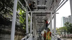 Pekerja menyelesaikan pembangunan bagian atap jembatan penyebrangan yang terhubung dengan halte busway BNN di Kawasan Cawang Jakarta, Jumat (2/3). (Liputan6.com/Faizal Fanani)