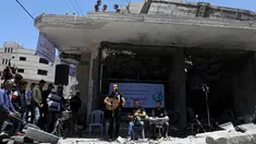 Seorang penyanyi Palestina tampil selama acara musik di puing-puing bangunan yang baru-baru ini hancur oleh serangan udara Israel di kota Gaza, Selasa (14/5/2019). Aksi tersebut untuk menyerukan pemboikotan terhadap Kontes Lagu Eurovision 2019 yang diselenggarakan di Israel. (REUTERS/Mohammed Salem)